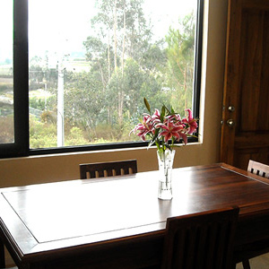 Dining area showing a wooden table, green curtains and kitchen in the background